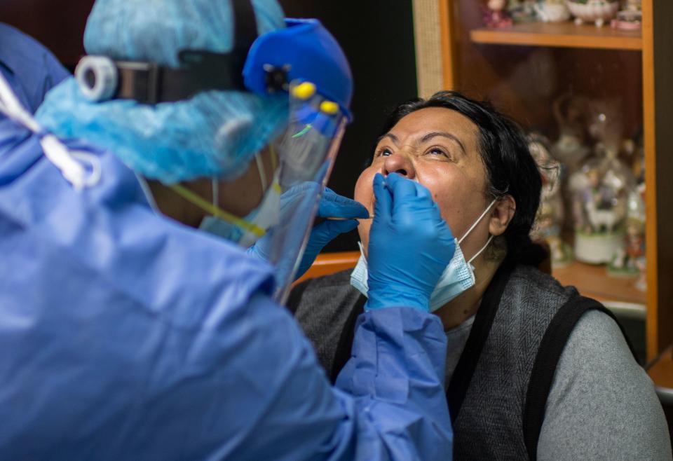 A health worker takes a sample from a woman, while on door-to-door visits to carry out COVID-19 tests in Mexico City, on June 16, 2020, amid the new coronavirus pandemic. (Photo by PEDRO PARDO / AFP) (Photo by PEDRO PARDO/AFP via Getty Images)