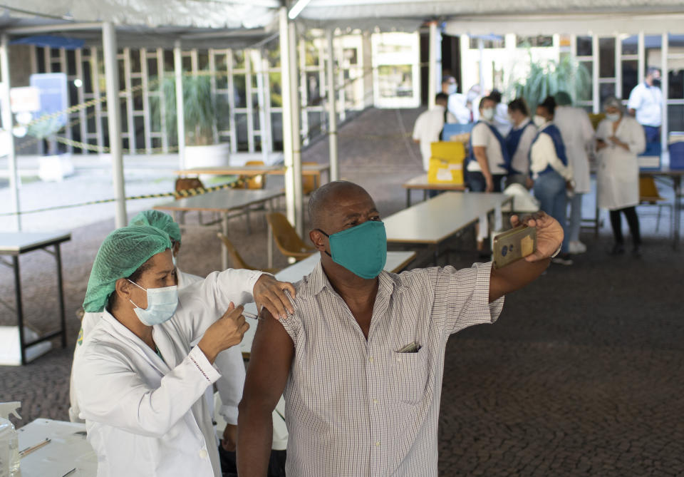 A man takes a selfie as he is injected with a dose of the AstraZeneca COVID-19 vaccine, at a vaccination site set up at the Federal University in Rio de Janeiro, Brazil, Wednesday, June 2, 2021. (AP Photo/Silvia Izquierdo)