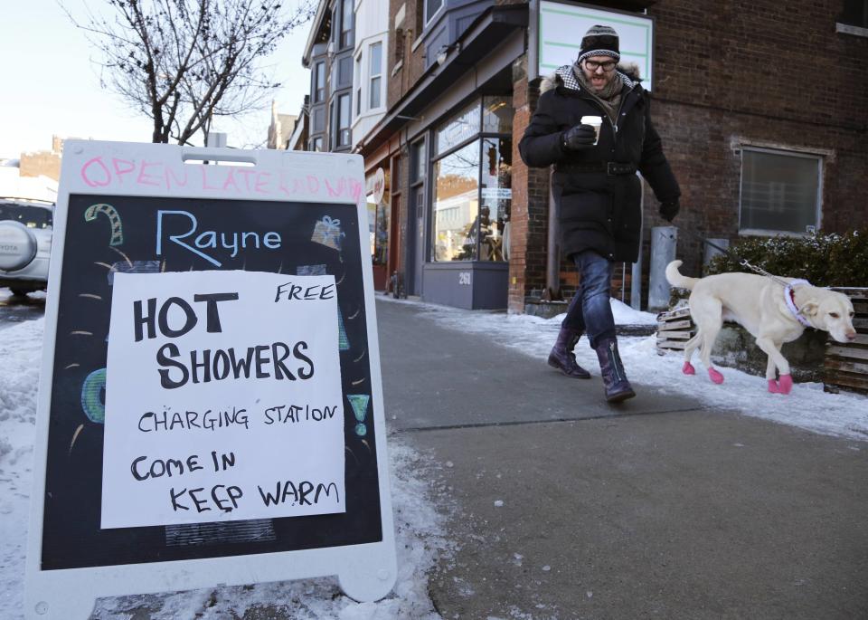 A man walks his dog past a spa advertising free hot showers for residents whose electricity remains knocked out by an ice storm in Toronto