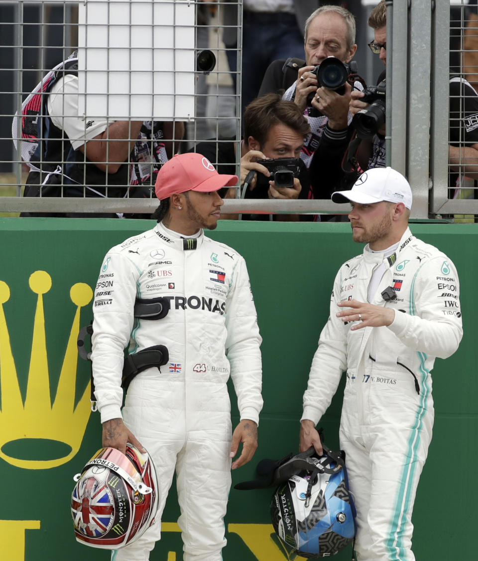 Mercedes driver Valtteri Bottas of Finland, right, speaks with second placed Mercedes driver Lewis Hamilton of Britain after he clocked the fastest time during the qualifying session at the Silverstone racetrack, in Silverstone, England, Saturday, July 13, 2019. The British Formula One Grand Prix will be held on Sunday. (AP Photo/Luca Bruno)