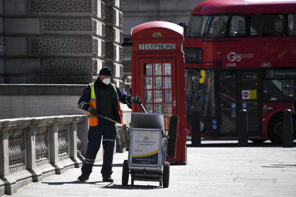 A council worker wearing a face mask to protect against coronavirus, collects refuse at Parliament Square, in London, Monday, May 18, 2020. Britain's Prime Minister Boris Johnson announced last Sunday that people could return to work if they could not work from home. (AP Photo/Alberto Pezzali)