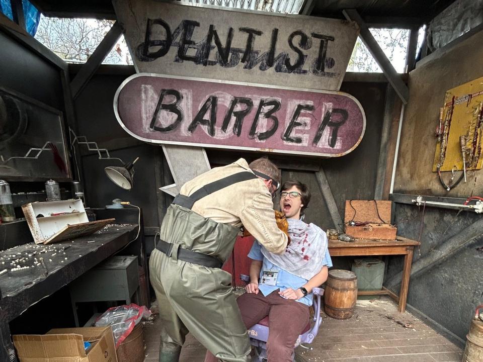 Dentist barber pulling teeth of man seated during Amazon interactive exhibition