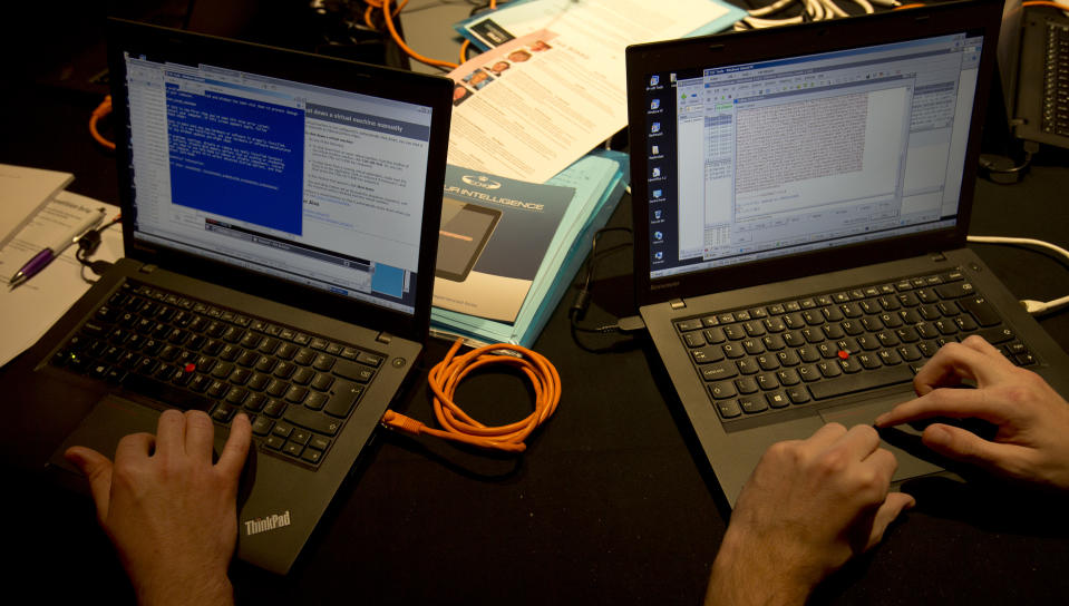 Members of 'team Red' work on laptop computers during a mock cyberattack scenario with teams of amateur computer experts taking part and trying to fight this simulated attack in London, Friday, March, 14, 2014. The exercise comes complete with sirens and mock newscasts. It's meant to recruit the next generation of tech talent, and is also meant to help highlight the threat many here see as inevitable: A major cyberattack on the nation's critical infrastructure. (AP Photo/Alastair Grant)