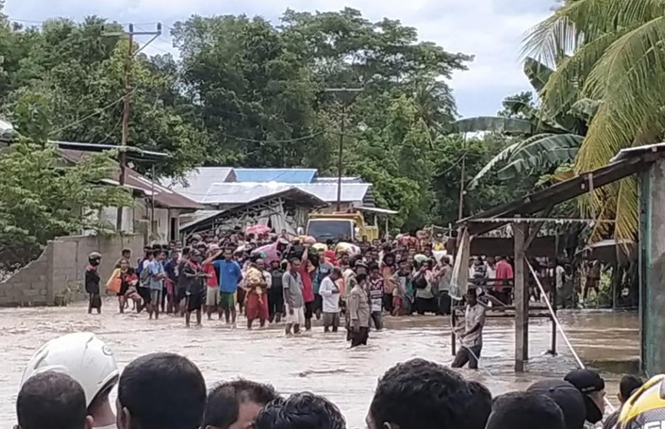 Residents wait for help to cross a flooded road in Malaka Tengah, East Nusa Tenggara province, Indonesia, Monday, April 5, 2021. Multiple disasters caused by torrential rains in eastern Indonesia have left dozens of people dead and missing and displaced thousands, the country's disaster relief agency said Monday. (AP Photo)