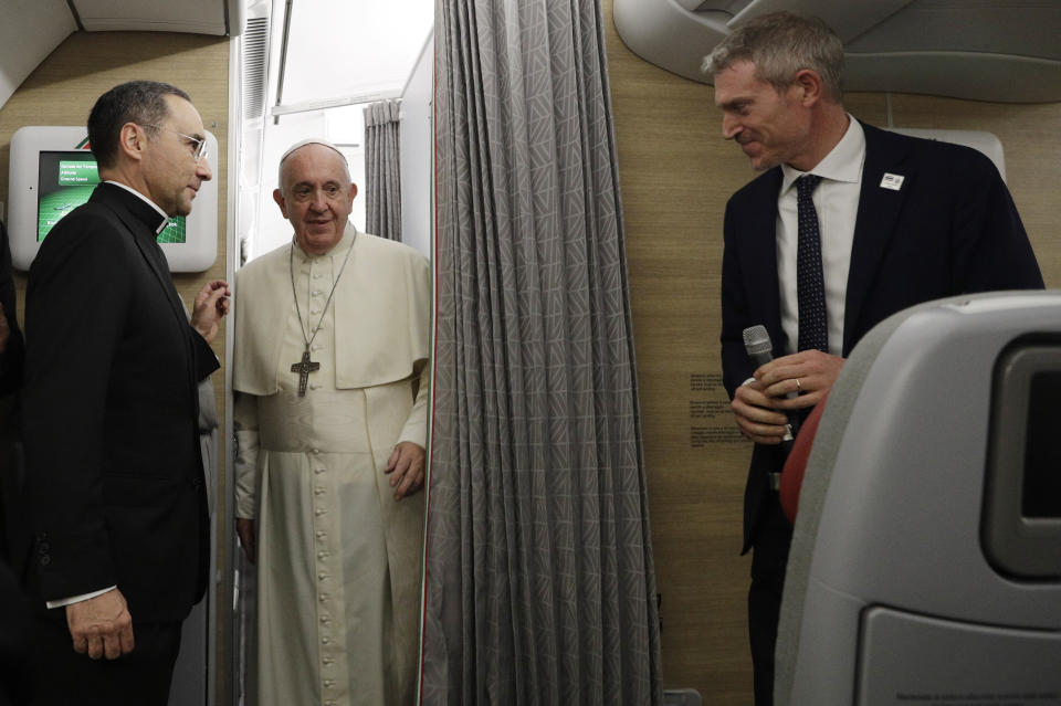 Monsignor Mauricio Rueda, left, and Vatican Spokesperson Matteo Bruni stand beside Pope Francis as he arrives to greet the journalists aboard of the papal plane heading to Bangkok on the occasion of the pontiff eight days pastoral trip to Thailand and Japan, Tuesday, Nov. 19, 2019. (AP Photo/Gregorio Borgia, Pool)