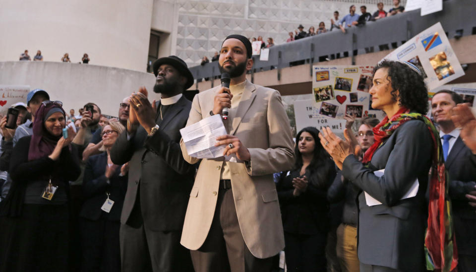 Imam Omar Suleiman speaks flanked by Dr. Michael W. Watson, left, and Rabbi Nancy Kasten, all from Faith Forward, at a vigil for refugees on Monday, Jan. 30, 2017 in Dallas, Texas at Thanksgiving Plaza.