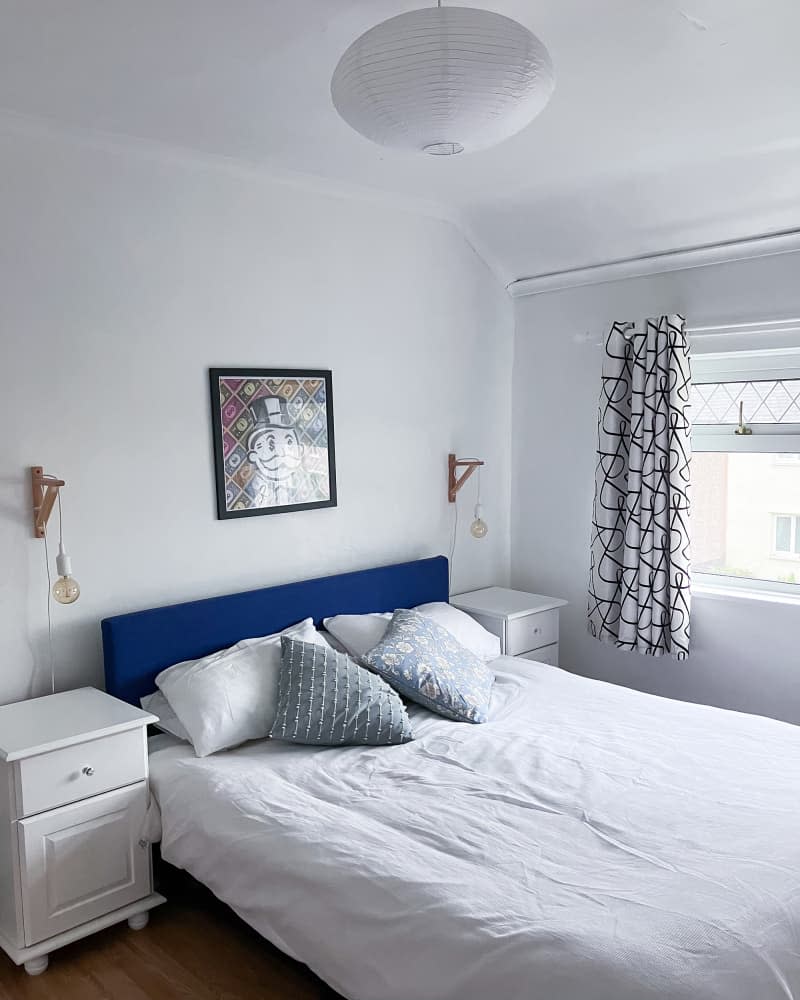 Paper lantern hanging in white bedroom with black and white graphic curtains.