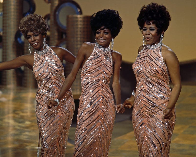 The Supremes (Cindy Birdsong, Diana Ross and Mary Wilson), wearing matching sequinned peach dresses with silver necklaces and earrings, during a live concert performance, circa 1965.