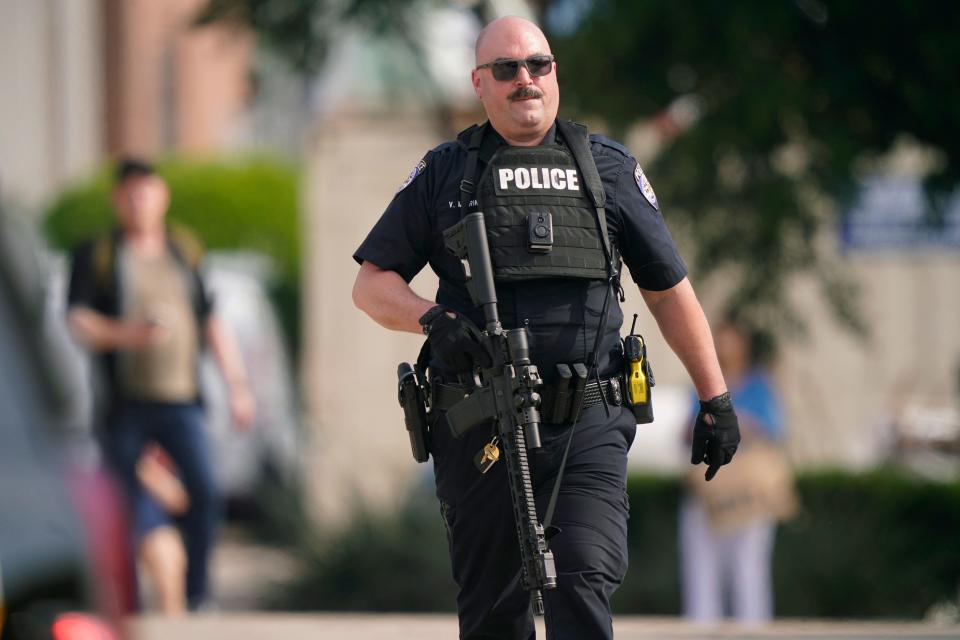 A law enforcement officer carries a rifle as people are evacuated from a shopping center where a shooting occurred Saturday, May 6, 2023, in Allen, Texas. (AP Photo/LM Otero)