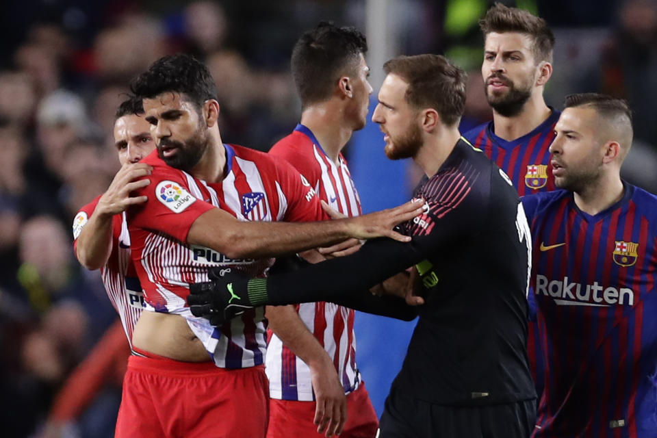 Atletico goalkeeper Jan Oblak, center right, tries to calm down teammate Diego Costa, left, after he was sent off with a red card for insulting referee Jesus Gil Manzano during a Spanish La Liga soccer match between FC Barcelona and Atletico Madrid at the Camp Nou stadium in Barcelona, Spain, Saturday April 6, 2019. (AP Photo/Manu Fernandez)