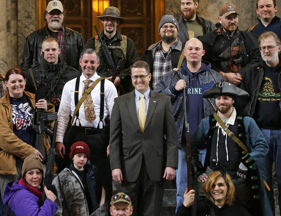 FILE - In this Jan. 15, 2015, file photo, Washington Rep. Matt Shea, R-Spokane Valley, center, poses for a group photo with gun owners inside the Capitol in Olympia, Wash., following a gun-rights rally. Recently published internet chats from 2017 show Shea and three other men discussing confronting "leftists" with a variety of tactics, including violence, surveillance and intimidation. The messages prompted Washington House Democrats to demand that Shea be reprimanded for a history of far-right speech and activities. (AP Photo/Ted S. Warren, File)