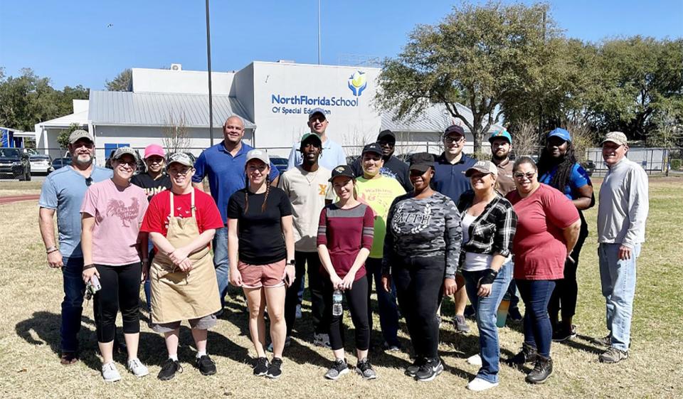 Andrew Hozier (front, second from left) gathers at the North Florida School of Special Education with volunteers from Ashley HomeStore. Hozier, who has Down syndrome, and the volunteers worked at the school's Barkin' Biscuit dog treat bakery.