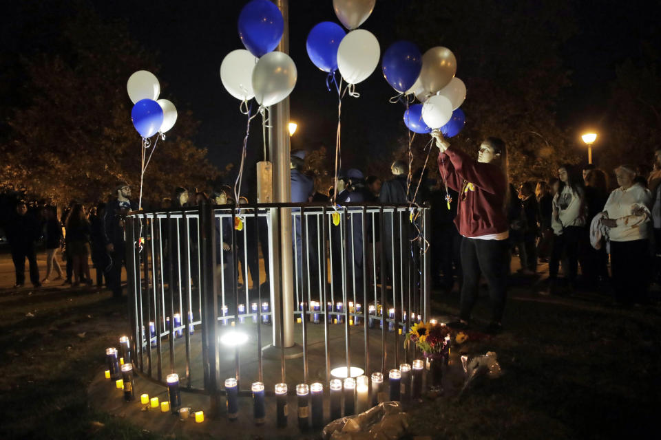 Jessica Dumont, a former student at Saugus High School, places balloons on a makeshift memorial at Central Park in honor of the victims of a shooting at the high school Thursday, Nov. 14, 2019, in Santa Clarita, Calif. Los Angeles County sheriff’s officials say a 16-year-old student shot several classmates and then himself in a quad area of Saugus High School Thursday morning. (AP Photo/Marcio Jose Sanchez)