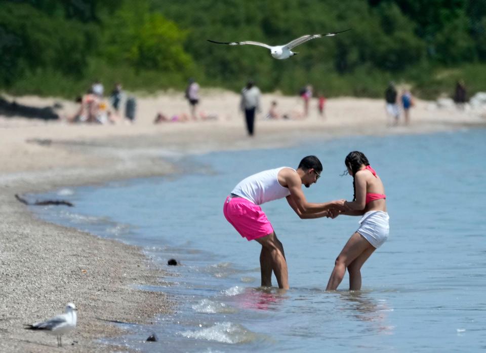 Jenuel Martinez (left) and his girlfriend, Nahomi Mendoza, of Milwaukee, play in the water near the shoreline at Bradford Beach on North Lincoln Memorial Drive in Milwaukee on Thursday. There will be no lifeguards at the popular summer spot.