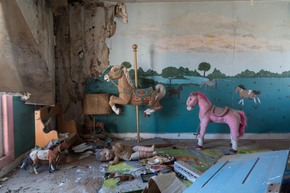 The interior of an abandoned house with toy horses.