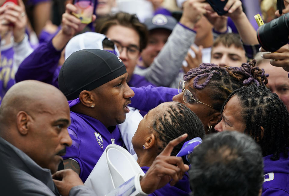 Washington quarterback Michael Penix Jr., center left, is mobbed by family and fans storming the field after a 36-33 victory over Oregon in an NCAA college football game, Saturday, Oct. 14, 2023, in Seattle. (AP Photo/Lindsey Wasson)