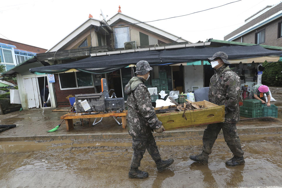 Army soldiers carry debris from a damaged house following flooding from heavy rains in Cheorwon, South Korea, Thursday, Aug. 6, 2020. Torrential rains continuously pounded South Korea on Thursday, prompting authorities to close parts of highways and issue a rare flood alert near a key river bridge in Seoul. (AP Photo/Ahn Young-joon)