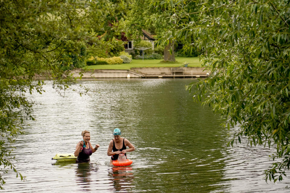 Susan Barry, left, and Jo Robb, members of the open water swimming group Henley Mermaids, exit the river Thames after a swim, in Henley-on-Thames, England, Friday, June 14, 2024. Britain has become notorious as a place where a casual swim could lead to an extended visit to the toilet, if not the hospital. A torrent of news on dirty water has spilled into next month's election to determine which party controls government for the next four or five years. (AP Photo/Alberto Pezzali)