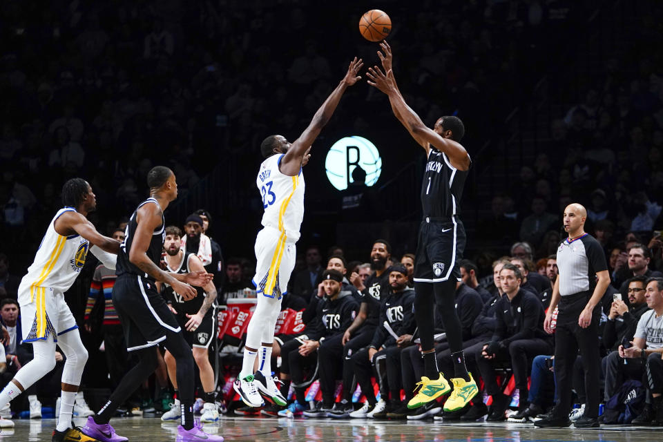 Golden State Warriors' Draymond Green (23) defends a three-point shot by Brooklyn Nets' Kevin Durant (7) during the first half of an NBA basketball game Wednesday, Dec. 21, 2022 in New York. (AP Photo/Frank Franklin II)