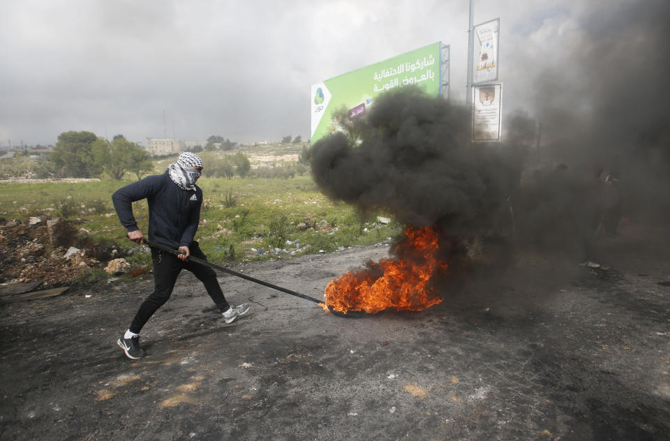 A Palestinian protester burns a tyre during a clashes with Israeli troops during demonstration in support of Palestinian prisoners held in Israeli jails at checkpoint Bet El near the West Bank city of Ramallah , Wednesday, March 27, 2019.(AP Photo/Majdi Mohammed)