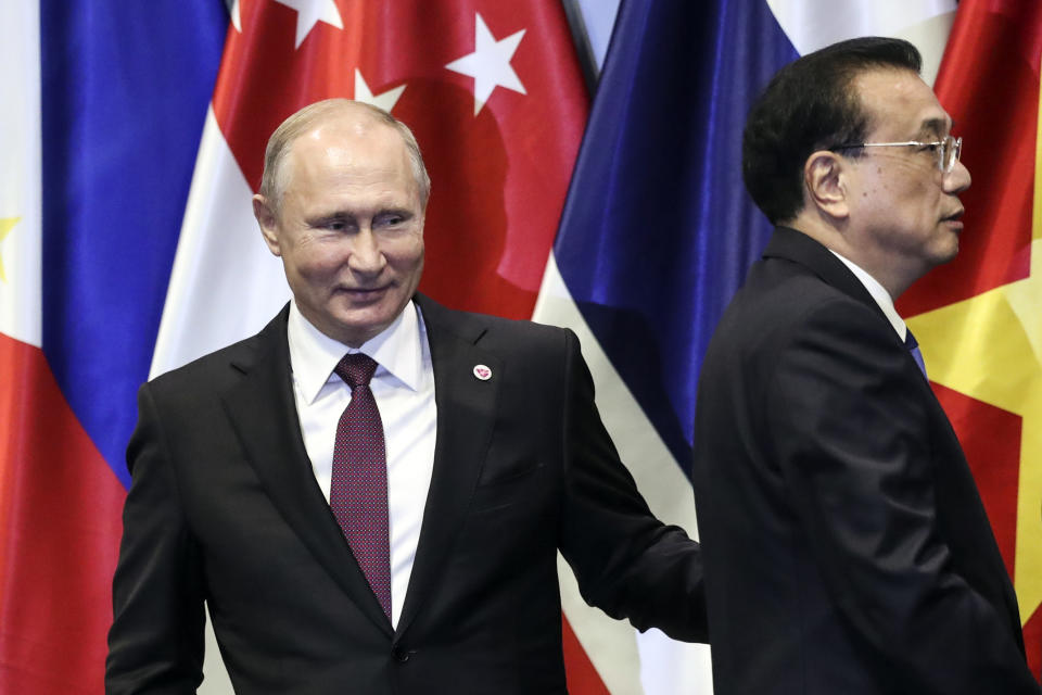 In this Thursday, Nov. 15, 2018, file photo, Russian President Vladimir Putin, left, and Chinese Premier Li Keqiang interacts on stage after a group photo during the 13th East Asian Summit Plenary on the sidelines of the 33rd ASEAN summit in Singapore. (AP Photo/Yong Teck Lim, File)