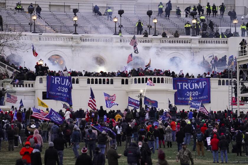 FILE - Violent insurrectionists loyal to President Donald Trump storm the Capitol, Jan. 6, 2021, in Washington. An Ohio man charged with stealing a coat rack from the U.S. Capitol doesn't deny that he joined the mob that stormed the building last year. But a lawyer for Capitol riot defendant Dustin Thompson vows to show that former President Donald Trump abused his power to authorize the attack on Jan. 6. (AP Photo/John Minchillo, File)