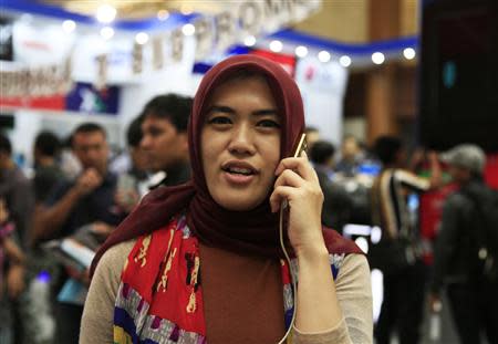 A woman uses her mobile during the Digital Imaging Expo in Jakarta March 5, 2014. REUTERS/Beawiharta