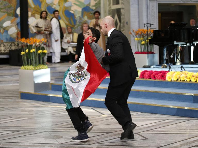 A security officer (right) leads away a man displaying a flag of Mexico during the Nobel Peace Prize awards ceremony at the City Hall in Oslo, Norway, on December 10, 2014