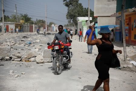 People walk along a road blocked by rocks in Croix-des-Bouquets, Haiti, July 8, 2018. REUTERS/Andres Martinez Casares