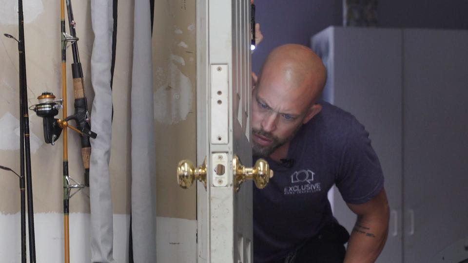 Home inspector Joe Mazza checks the hinges of a garage door. Mazza recommends all homes have a fire-rated garage door that automatically shuts to isolate the garage from the remainder of the home.