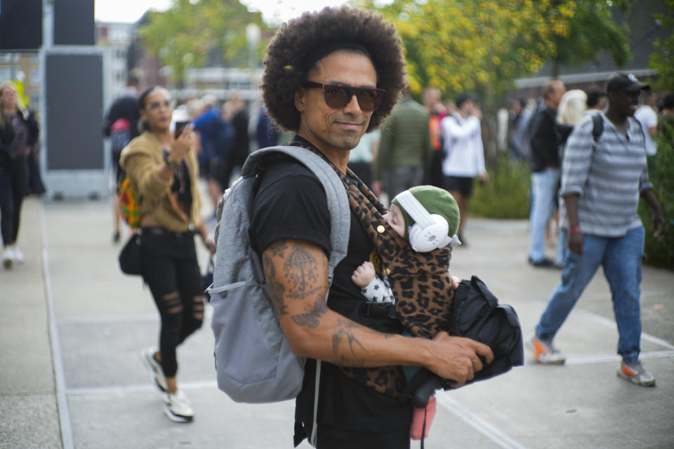 A father carrying his baby with ear protection keeps a safe distance as he joins a protest of organizers and fans of music festivals stage against the government's COVID-19 restrictions on large-scale outdoor events in Amsterdam, Netherlands, Saturday, Sept. 11, 2021. On Saturday, the festivals came to music fans as hundreds of performers and festival organizers called again for demonstration marches through Dutch cities to protest what they argue are unfair restrictions that have forced the cancellation of summer festivals and other events. (AP Photo/Peter Dejong)