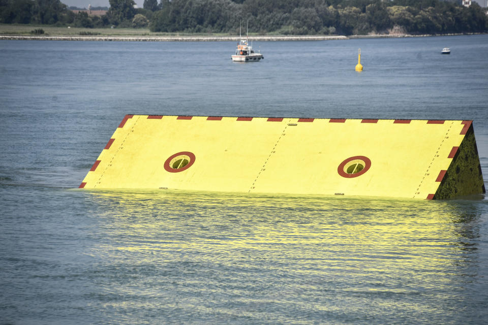 Moveable flood gates rise from the sea in the Venice lagoon, Italy, Friday, July 10, 2020. Venice has conducted a trial run an ambitious anti-flood system of 78 inflatable barriers in the hopes of protecting the lagoon city from devastating high tides. Premier Giuseppe Conte on Friday at a ceremony in Venice pressed a button that activated compressors to pump air into the bright yellow barriers, which then started rising from the sea to act a kind of a dike-on-demand. (Claudio Furlan/LaPresse via AP)