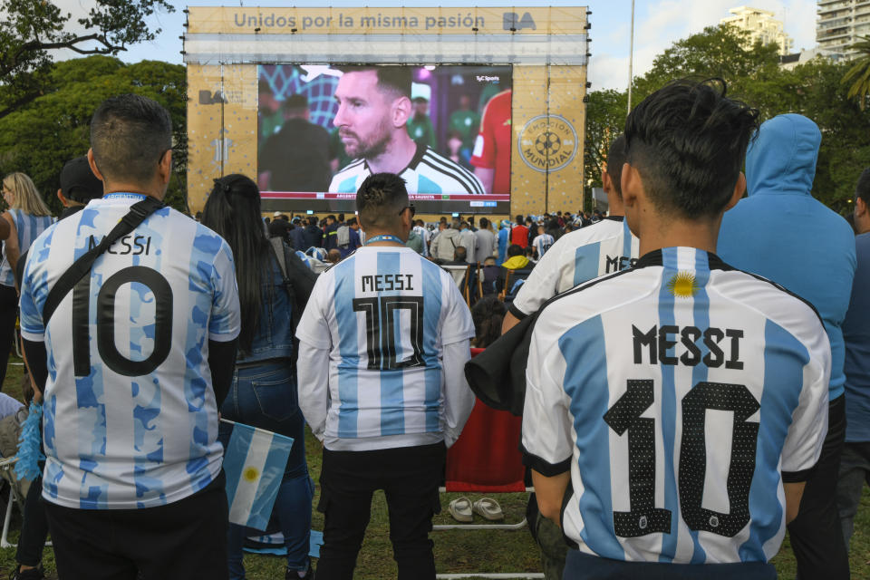Argentina soccer fans wearing Lionel Messi jerseys watch their team lose to Saudi Arabia in a World Cup Group C soccer match, played on a large screen in the Palermo neighborhood of Buenos, Aires, Argentina, early Tuesday, Nov. 22, 2022. (AP Photo/Gustavo Garello)