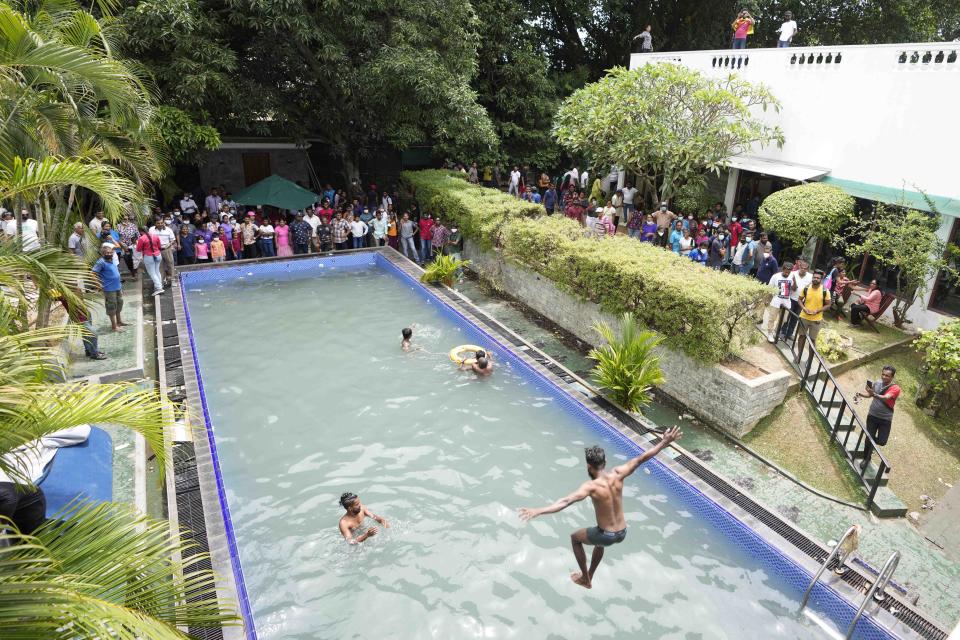 Protesters swim as onlookers wait at a swimming pool in the president's official residence a day after it was stormed in Colombo, Sri Lanka, Sunday, July 10, 2022. Sri Lanka’s opposition political parties will meet Sunday to agree on a new government a day after the country’s president and prime minister offered to resign in the country’s most chaotic day in months of political turmoil, with protesters storming both officials’ homes and setting fire to one of the buildings in a rage over the nation’s economic crisis. (AP Photo/Eranga Jayawardena)