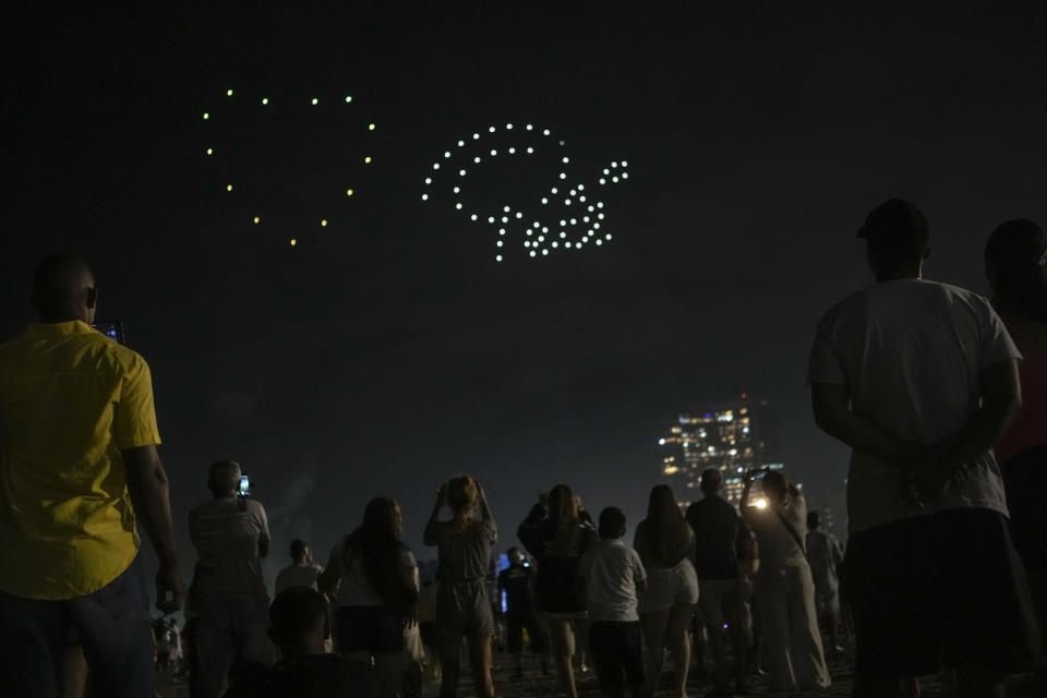 People watch a drone show in homage to the late Brazilian soccer star Pele, over Gonzaga Beach in Santos, Brazil, Saturday, Dec. 31, 2022. Pele, who played most of his career with Santos, died in Sao Paulo on Thursday at the age of 82. (AP Photo/Matias Delacroix)