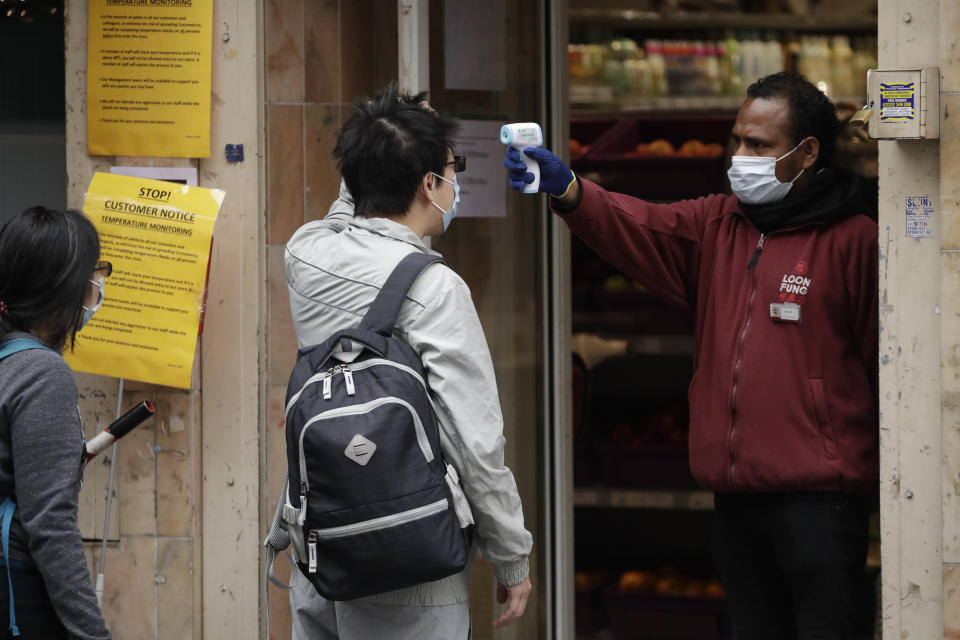 Un empleado le toma la temperatura a un cliente en un establecimiento de Chinatown, Londres (AP /Matt Dunham)