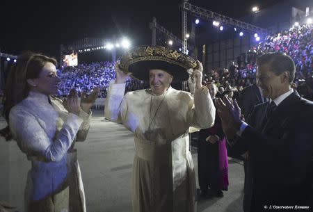 Pope Francis (C) wears a sombrero hat as he meets Mexico's President Enrique Pena Nieto (R) and first lady Angelica Rivera after his arrival in Mexico City, February 12, 2016. REUTERS/Osservatore Romano Handout via Reuters