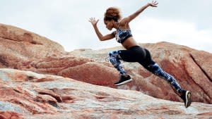 Female athlete running in a rocky environment wearing running clothes