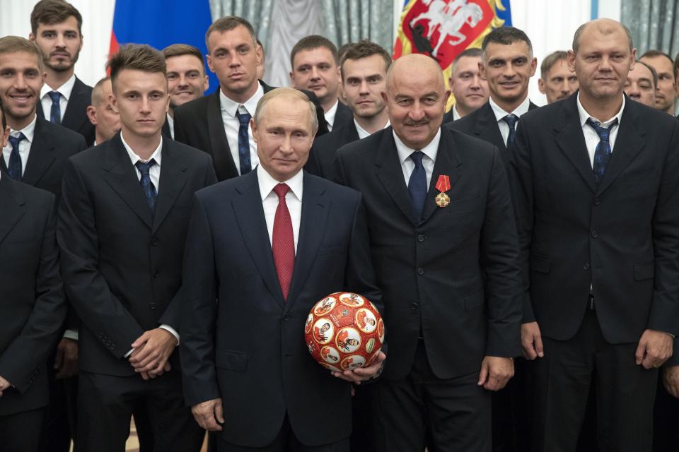 FILE - Russian President Vladimir Putin, center left, and Russia's soccer team head coach Stanislav Cherchesov, center right, goalkeeper Igor Akinfeev, second row center, soccer players Alexander Golovin, second from left, Artem Dzyuba, second row third from left, pose for a photo during the State Prize awards ceremony in Kremlin in Moscow, Russia, Saturday, July 28, 2018. Russian teams have been suspended from all international soccer, including qualifying matches for the 2022 World Cup, as Moscow was pushed toward pariah status in sports for its invasion of Ukraine. World soccer body FIFA and European authority UEFA banned Russian national and club teams from their competitions "until further notice," taking Russia's men's national team out of World Cup qualifying playoffs in three weeks' time. (AP Photo/Pavel Golovkin, Pool, File)