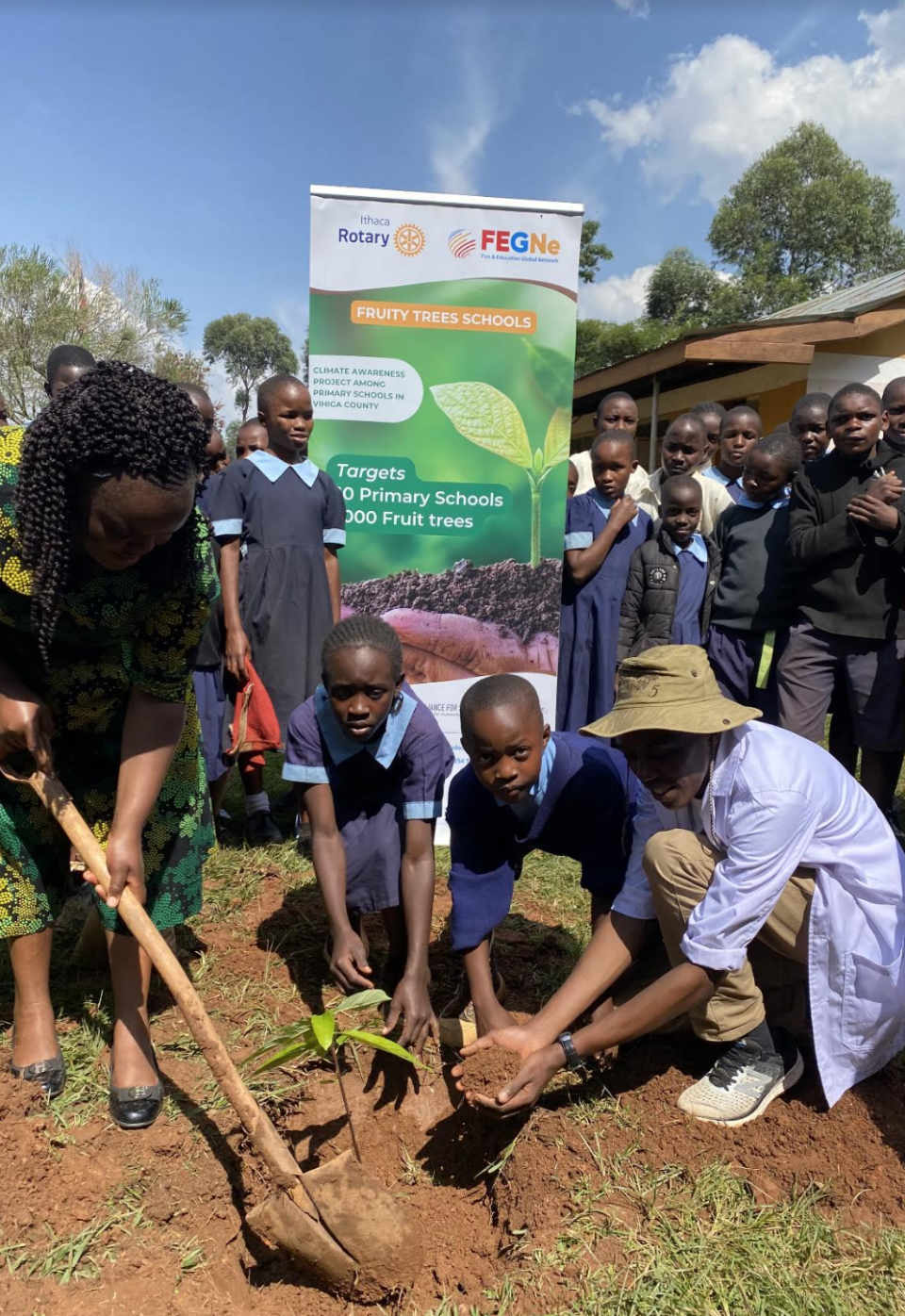 Kenyan students plant a fruit tree following a $5,000 grant award from the Ithaca Rotary Club.