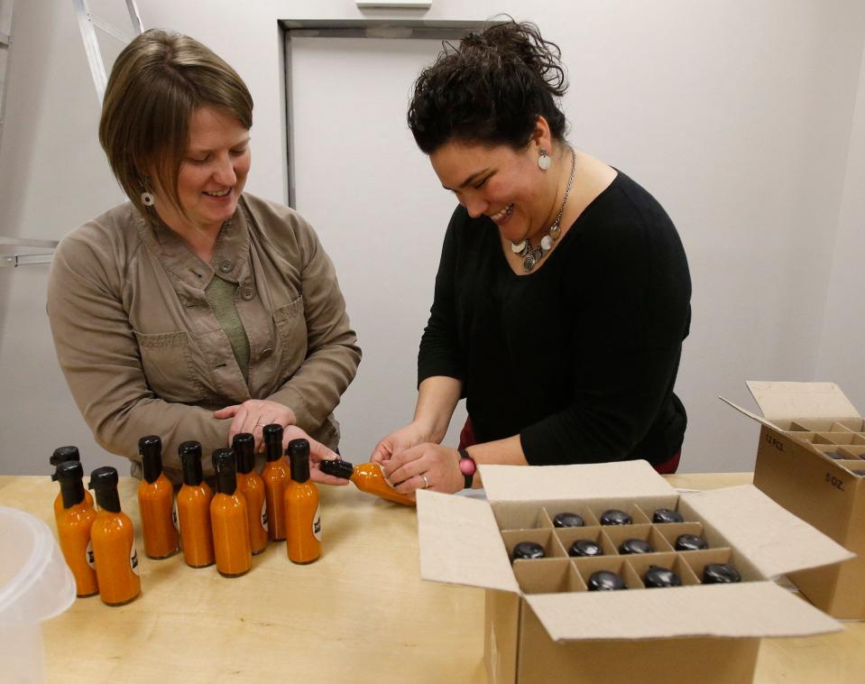 Rachelle Wardell, left, and Christina Gonzalez, makers of Not Yo Daddy's Mexican Hot Sauce, label bottles of their hot sauce.