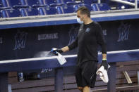 FILE - In this Thursday, July 16, 2020, file photo, a worker sprays the dugout rail to help prevent the spread of the coronavirus, before the Miami Marlins' baseball practice at Marlins Park in Miami. The Marlins, one of the most under-the-radar teams in sports, have making news lately, all of it bad. Overtaken by a coronavirus outbreak, the team must scramble for roster replacements as they try salvage a season barely underway. (AP Photo/Wilfredo Lee, File)