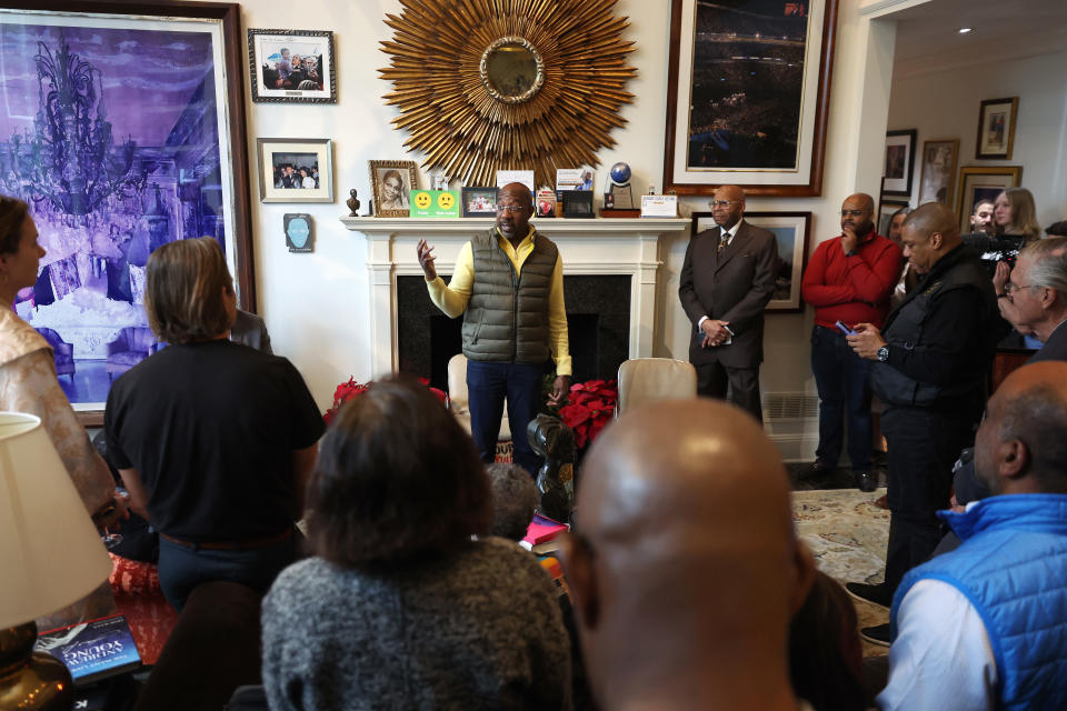 Sen. Raphael Warnock stands in front of a fireplace mantel at a meet-and-greet campaign event with supporters on Nov. 26 in Atlanta. 