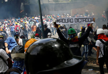 A demonstrator holds a sign that reads 'Maduro dictator' at a rally against Venezuela's President Nicolas Maduro in Caracas, Venezuela. REUTERS/Carlos Garcia Rawlins