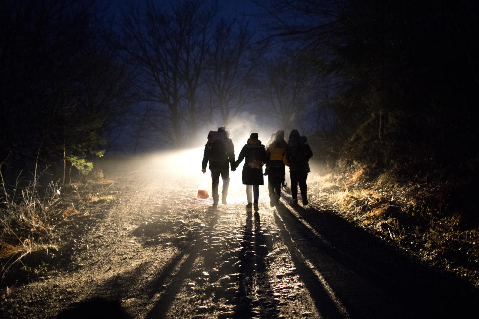 In this picture taken Thursday Dec. 12, 2019, Indian migrants Nishademi, 22, and Suhil, 23, walk with Saif, 33, Fatma, 24, and their son Omar, 1, Syrian refugees form Aleppo walk towards the border with Croatia as they attempt to enter the EU in the mountains surrounding the town of Bihac, northwestern Bosnia. (AP Photo/Manu Brabo)