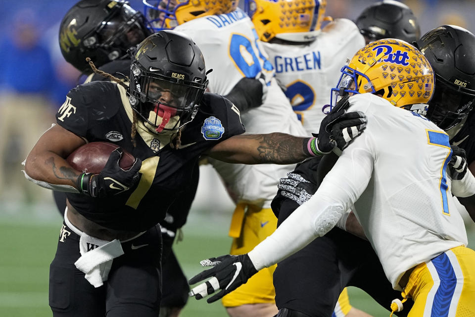 Wake Forest running back Christian Beal-Smith pushes past Pittsburgh linebacker SirVocea Dennis during the first half of the Atlantic Coast Conference championship NCAA college football game Saturday, Dec. 4, 2021, in Charlotte, N.C. (AP Photo/Chris Carlson)