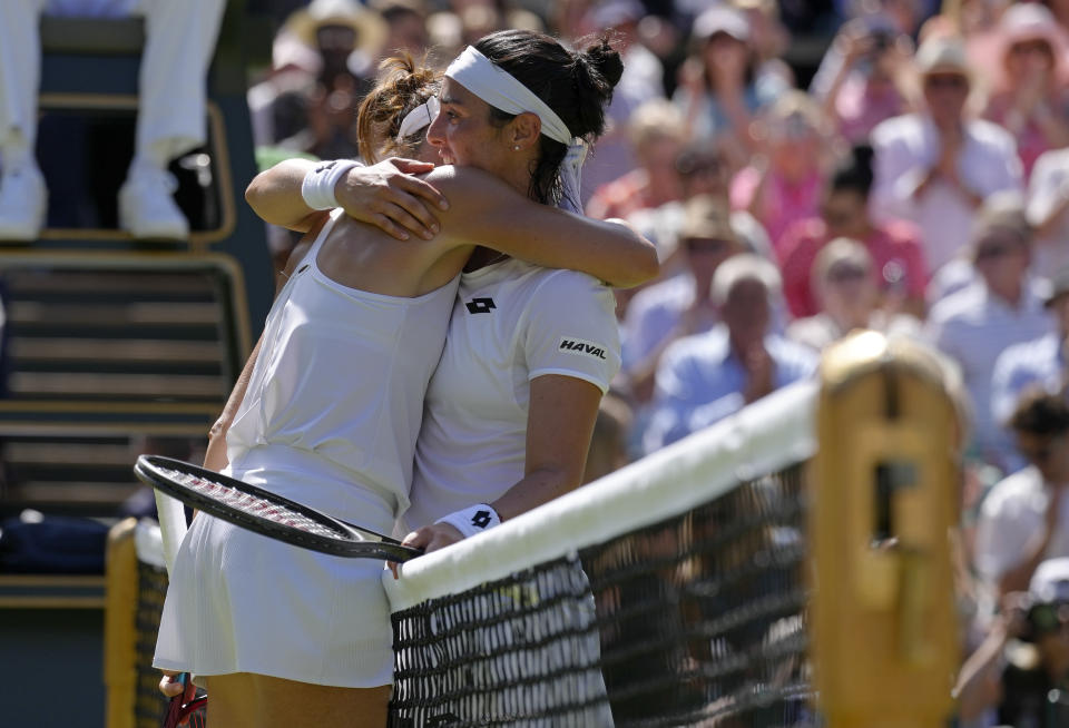 Tunisia's Ons Jabeur, right, embraces Germany's Tatjana Maria at the net after beating her in a women's singles semifinal match on day eleven of the Wimbledon tennis championships in London, Thursday, July 7, 2022. (AP Photo/Kirsty Wigglesworth)