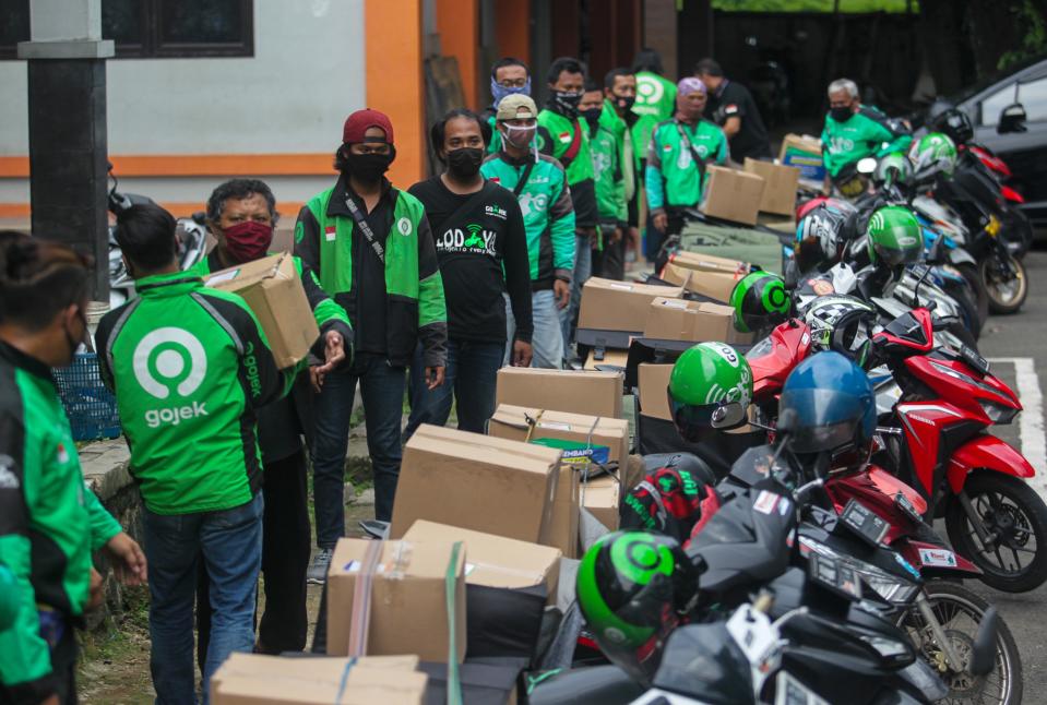 Gojek driver distributes foodstuffs to residents affected by COVID-19 outbreaks, in Bogor, Indonesia, June 5, 2020. The Indonesian government distributes food aid to people affected by Coronavirus outbreaks, through online transportation operators. (Photo by: Aditya Saputra/INA Photo Agency/Universal Images Group via Getty Images)