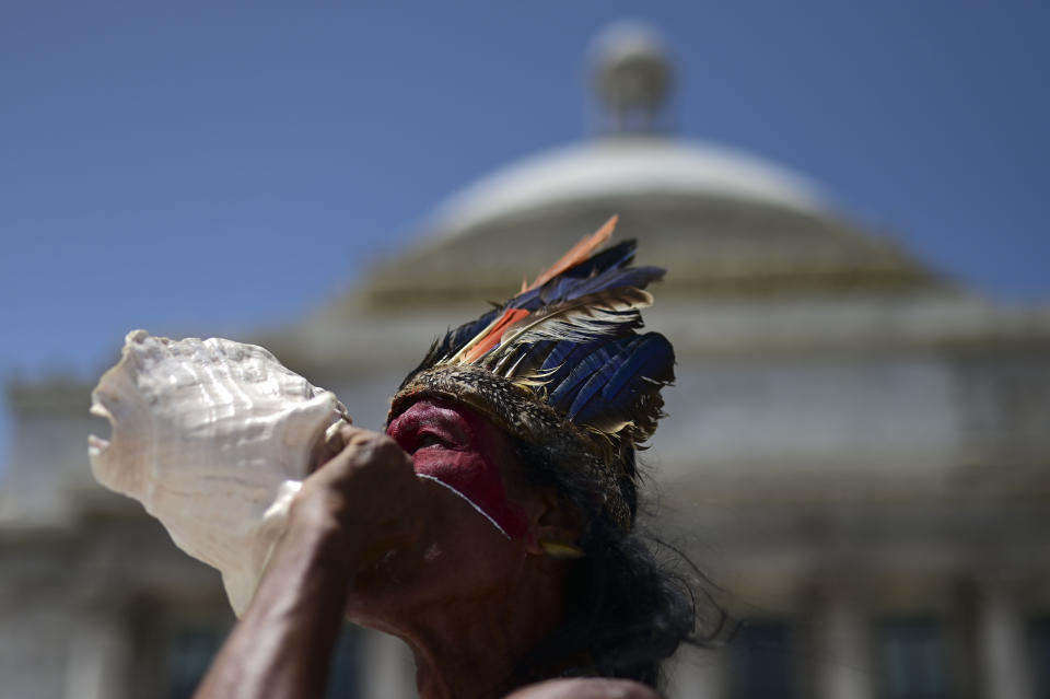 Baracutey blows on a conch shell outside the Capitol building while joining a group of activists demanding statues and street names commemorating symbols of colonial oppression be removed, in San Juan, Puerto Rico, Saturday, July 11, 2020. Dozens of activists marched through the historic part of Puerto Rico’s capital on Saturday to demand that the U.S. territory’s government start by removing statues, including those of explorer Christopher Columbus. (AP Photo/Carlos Giusti)