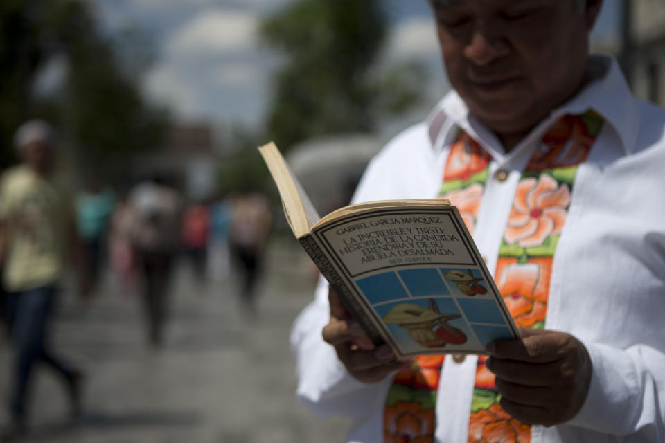 A man reads a book by Colombian Nobel Literature laureate Gabriel Garcia Marquez as he waits in line to pay his respects to the author at the Palace of Fine Arts in Mexico City, Monday, April 21, 2014. The ashes of Garcia Marquez were taken Monday to Mexico City's majestic Palace of Fine Arts, where thousands of admiring readers began paying tribute to the Colombian Nobel laureate considered one of the greatest Spanish-language authors of all time. (AP Photo/Rebecca Blackwell)